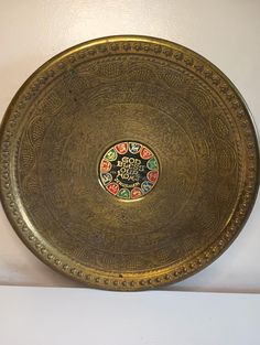 a gold plate with an ornate design on the front and sides, sitting on a white surface