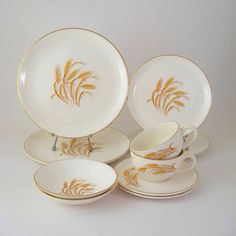 a set of four plates and cups with gold designs on the rims, all in different shapes and sizes