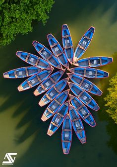 several boats are lined up in the middle of a lake with trees around them and one boat is upside down