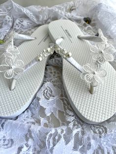 These beautiful flip flops are wrapped in white satin ribbon, and adorned with 3 white flowers and pearls on each side. Ribbon color is white, if you are needing other colors of ribbon or decoration please contact me and will be happy to accommodate you! All flip flops are handmade to order and the production time 1 to 2 weeks and then please allow additional time for shipping. Amazing for beach, weddings, flower girl or a fancy event, you choose! Please choose your size from the drop box. Summer Wedding Closed Toe Shoes For Ceremony, Summer Wedding Closed-toe Shoes, White Sandals For Beach Wedding In Spring, White Sandals For Summer Ceremonies, Pearl White Summer Wedding Shoes, Summer Wedding Open Toe Shoes For Ceremony, White Summer Ceremony Sandals, White Round Toe Beach Wedding Shoes, Elegant Silver Flip Flops For Summer