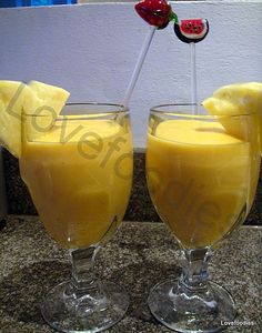 two glasses filled with yellow liquid on top of a counter