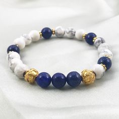 "This lovely bracelet features Howlite and Lapis Lazuli 8mm beads with 22K gold-plated spacer beads, and two intricate 22K gold-plated beads flanking the central three Lapis beads. Howlite is a calming stone, and facilitates emotional expression. Lapis Lazuli is said to activate psychic abilities and intuition. This bracelet will roll on and roll off easily, as it is made with strong stretch cord, secured with a triple square knot hidden under a bead. I guarantee all of my work. Choose your size from the drop-down menu. A medium, 7.5\", will fit most women's wrists.  To measure your wrist, use a tape measure or a piece of string to measure your wrist just above (towards your elbow) your wrist bone. Then add one inch for a snug fit, and 1.5 inches for a looser fit: that's your bracelet size Gold Lapis Lazuli Beaded Bracelets With Round Beads, Gold Lapis Lazuli Spiritual Bracelets, Gold Stretch Bracelet With 8mm Beads For Meditation, Gold Stretch Bracelet With Natural Stones For Meditation, White And Blue Bracelet, Blue Gemstone Bracelet, Fluorite Bracelet, Emotional Expression, Empath Protection