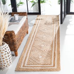 a large area rug in the middle of a room with wicker furniture and plants