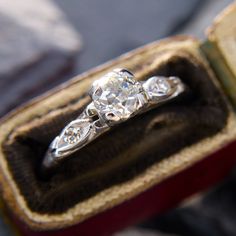 an engagement ring with three diamonds in it sitting inside a box on top of a table