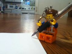 a lego figurine holding a giant knife on top of a piece of paper