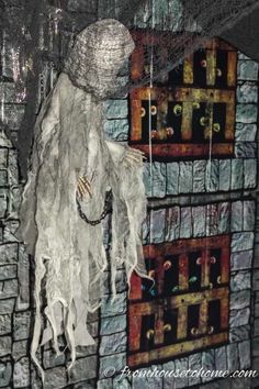 there is a ghost hanging from the side of a brick wall with chains and beads