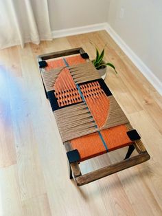 an orange and black piece of art sitting on top of a wooden table next to a potted plant