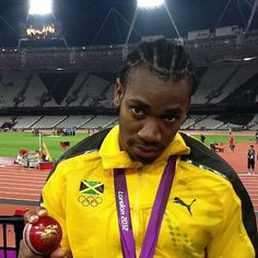 a man in a yellow jacket holding a red ball and a gold medal on his left hand