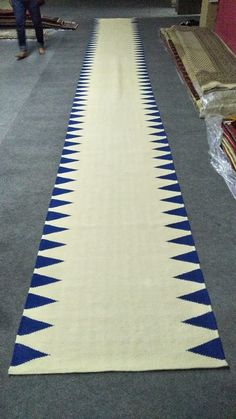 a long white and blue rug on the floor in a room with two people standing next to it