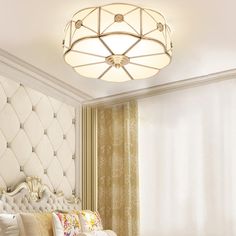 a white bed sitting under a round light fixture