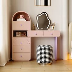 a pink desk with a mirror, stool and other furniture in a room that has white walls