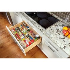 an open drawer in the middle of a kitchen counter with spices and fruit on it