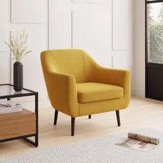 a yellow chair sitting on top of a hard wood floor next to a glass table