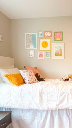 a white bed sitting in a bedroom next to a wall with many pictures on it