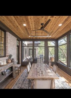 a dining room table with chairs and a ceiling fan in front of windows that look out onto the outdoors