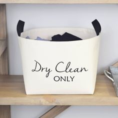 a white canvas laundry basket with dry clean only written on the front in black ink