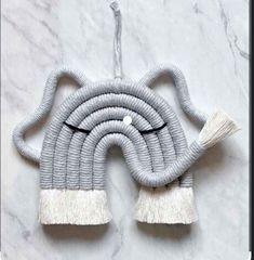 a gray and white rope with tassels hanging on a marble wall ornament