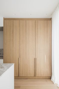 an empty room with wooden cabinets and marble counter top in front of the door to the kitchen