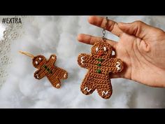 two crocheted gingerbreads are being held up by someone's hand