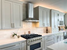 a kitchen with white cabinets and stainless steel stove top oven in the middle of it