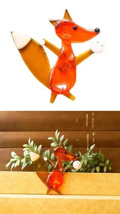 an orange fox figurine sitting on top of a wooden box next to a plant