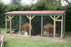 a chicken coop in the middle of a yard with two chickens inside and one dog on the other side