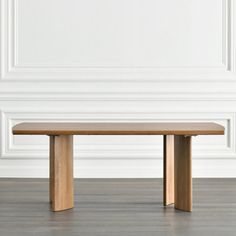 a wooden table sitting on top of a hard wood floor next to a white wall