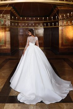 a woman in a white wedding dress standing on a tiled floor with chandelier