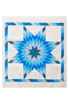 a blue and white quilt with a star design on the center, in front of a white background