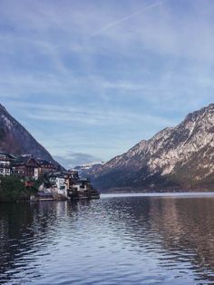 a lake with mountains in the background and houses on the shore near it, surrounded by snow capped mountains