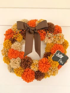 an orange and brown wreath hanging on the side of a door with a sign that says autumn fling