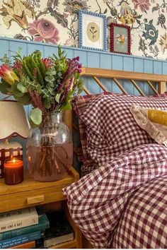 a bed room with a neatly made bed and a vase filled with flowers on top of it