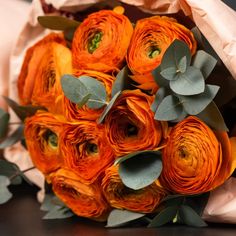 a bouquet of orange flowers with green leaves