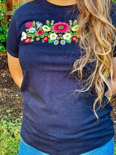 a woman with long blonde hair wearing a blue t - shirt that has flowers on it