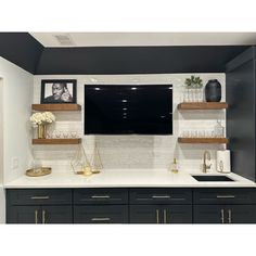 a kitchen with black cabinets and white counter tops is shown in this image, there are pictures on the wall above the sink