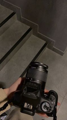 a person holding up a camera in front of their face with stairs behind them on either side