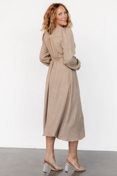 Casual and stylish all in one dress Lightweight linen-like material Neutral taupe color V-neckline Buttoned placard down front of dress Gathering at bust, shoulder yoke, and across back Long sleeves with single buttons at cuffs Upturned, paneled V-waistband with subtle gathering underneath Elastic at back waist Unlined 63% Recycled Polyester, 37% Polyester Marianne is 5'6, cup size 34D, size 6 and wearing size S Beige Button-up Daywear Dress, Modest Beige V-neck Dress, Chic Long Sleeve Beige Linen Dress, Linen V-neck Midi Dress, Chic Beige Midi Linen Dress, Beige V-neck Dress For Work, Elegant Long Sleeve Beige Linen Dress, Chic Linen Midi Dress With Button Closure, Chic Beige Linen Long Sleeve Dress