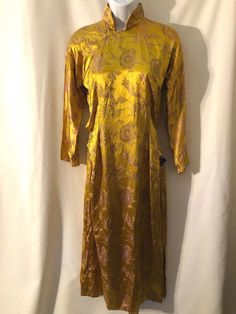 Beautiful Vintage Gold Chinese handmade silk long cheongsam. Handtailored. side slits Lined. Otherwise no stains, pulls, etc-from a smoke free home. Please see measurements for proper fit as all sales are final.  shoulders 19 length 49 hips 34 underarm to underarm 19 Ceremonial Silk Fitted Dresses, Traditional Formal Dress With Stand Collar, Silk Long Sleeve Ao Dai, Long Fitted Ceremonial Dress, Fitted Long Ceremonial Dress, Fitted Silk Ao Dai With Long Sleeves, Fitted Silk Long Sleeve Ao Dai, Gold Silk Dress For Transitional Season, Fitted Long Dress For Ceremonial Occasions