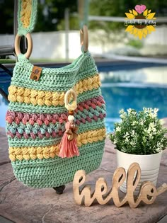 a crocheted purse sitting on top of a table next to a potted plant