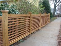 a wooden fence next to a sidewalk in front of a house