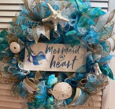 a wreath that says mermaid and heart on the front door with sea life around it