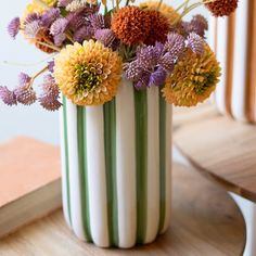 a vase filled with flowers sitting on top of a wooden table