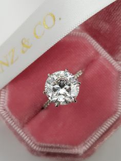 an engagement ring with a diamond in it sitting on a pink velvet box that says n y & co