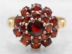 This yellow gold garnet cluster ring is a stunning addition to any jewelry collection. It features gorgeous garnets set in a cluster design, creating a beautiful and timeless piece. Crafted in yellow gold, this ring is a perfect balance of elegance and sophistication. Elevate your style with this luxurious ring. Metal: 18K Yellow Gold Gem: Garnets Gem Measurements: 4.7 mm, Round Ring Size: 7 Marks: "<750>" Stamped on the inside band SKU #: A42029 Each piece has been identified and graded by a Graduate Gemologist who has been certified by the Gemological Institute of America (GIA). We have six brick-and-mortar storefronts in Maine, Massachusetts, and New Hampshire and have been in business for over 25 years! Please visit our Shop's About Page or our website for more information about our je Yellow Gold Cocktail Ring, Right Hand Ring, Cluster Design, Garnet Gem, Gold Cocktail Ring, Gold Cocktail, Right Hand Rings, Hand Ring, Round Rings