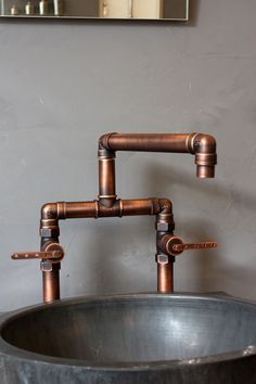 a metal sink with two faucets on the side and a mirror above it