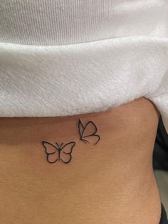 a woman's stomach with two small butterflies on the side of her belly,