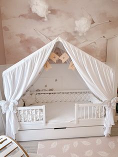 a baby's room with a white crib and clouds painted on the ceiling