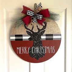 a merry christmas door hanger with a deer head and plaid ribbon on it's front door