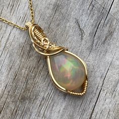 This gorgeous Ethiopian Opal pendant is hand wrapped using elegant 14k yellow gold filled wire. With a gray base, it has a stunning play of color consisting of orange, red, green, yellow, pink, and some light blue and purple in certain lighting. The opal weighs 7.35 carats before wrapped. This pendant measures about 1.5 inches tall from the bottom of pendant to the top of the bail. A complimentary 14k gold filled chain is included! Chain is removable and interchangeable. I did my best to provide Ethiopian Opal Gemstone Jewelry For Weddings, Handmade Ethiopian Opal Jewelry For Anniversary, Unique Hand Wrapped Jewelry For Anniversary, Hand Wrapped Spiritual Jewelry For Anniversary, Spiritual Hand Wrapped Jewelry For Anniversary, Teardrop Ethiopian Opal Jewelry Gift, Handmade Ethiopian Opal Elegant Jewelry, Ethiopian Opal Birthstone Jewelry As Gift, Elegant Hand Wrapped Pendant Jewelry