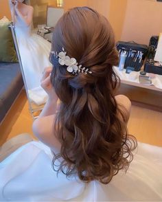 a woman with long brown hair wearing a flowered headpiece in front of a mirror